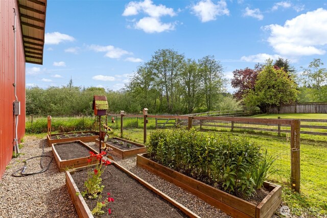 view of yard featuring a garden, fence, and a view of countryside