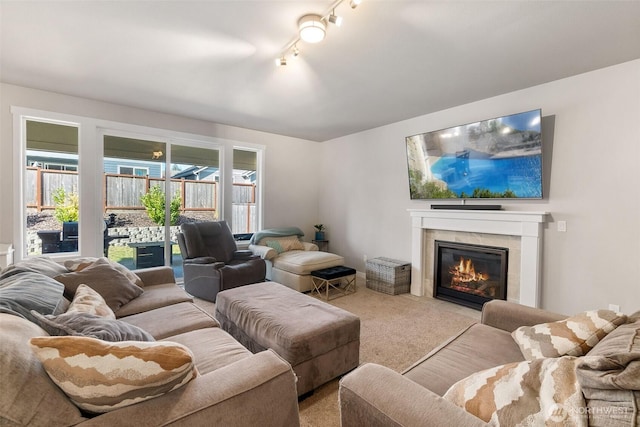 living area with a tiled fireplace, carpet, and rail lighting