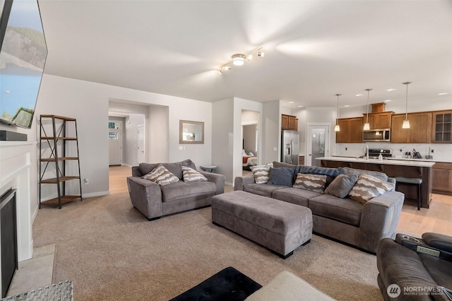 living area featuring a high end fireplace, baseboards, and light colored carpet