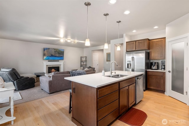 kitchen with light countertops, light wood-style floors, appliances with stainless steel finishes, and a sink