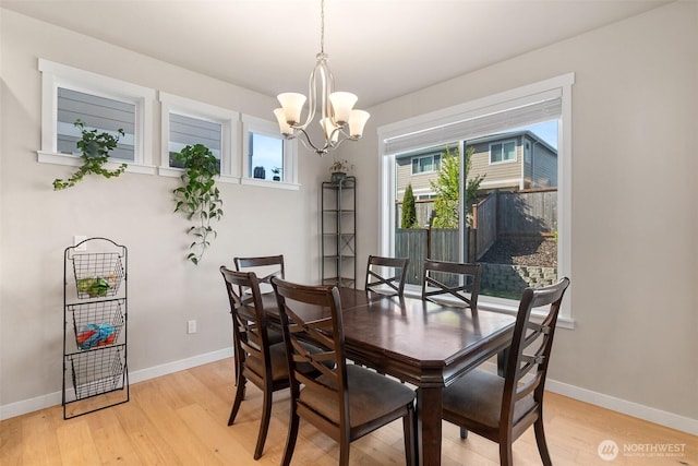 dining space with baseboards, an inviting chandelier, and light wood-style flooring