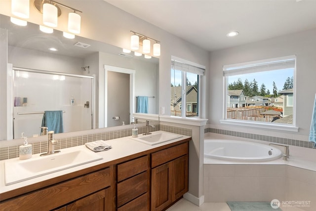 full bath featuring double vanity, a shower stall, a garden tub, and a sink