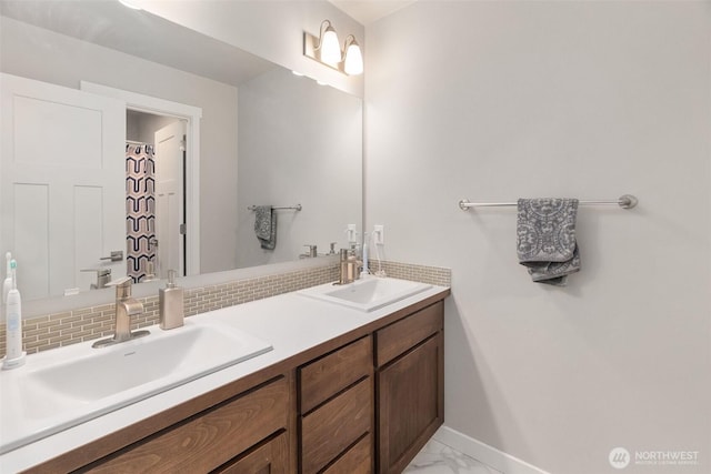 bathroom with marble finish floor, baseboards, decorative backsplash, and a sink