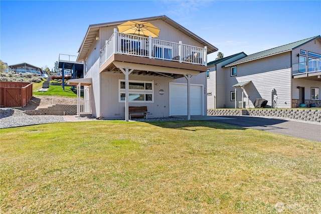 rear view of house with an attached garage, driveway, and a yard