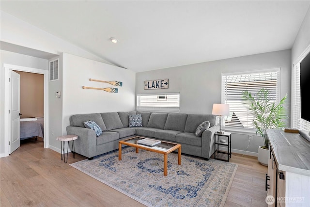 living room with baseboards, light wood finished floors, vaulted ceiling, and visible vents