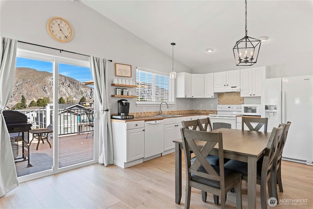 dining area featuring high vaulted ceiling, an inviting chandelier, a mountain view, and light wood-style flooring