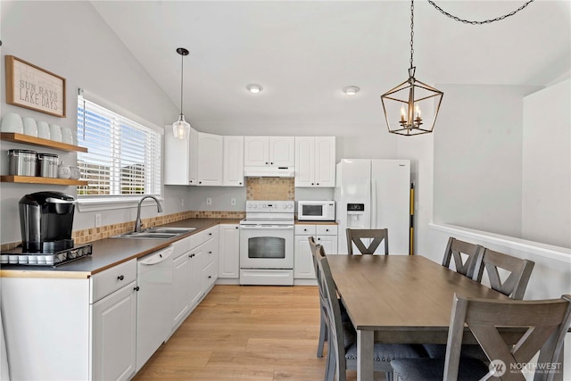kitchen featuring white cabinets, a chandelier, a sink, and white appliances