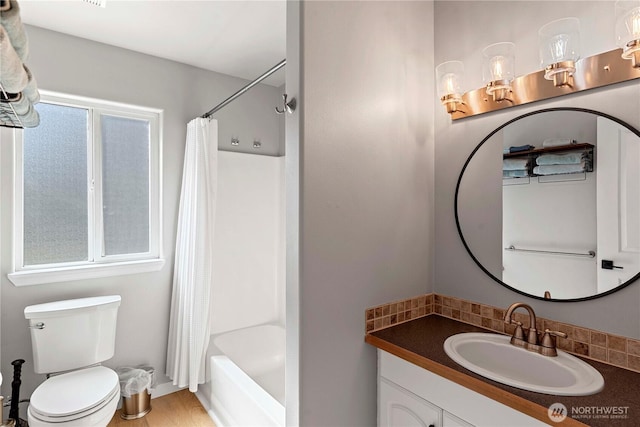 bathroom featuring backsplash, wood finished floors, toilet, vanity, and shower / tub combo