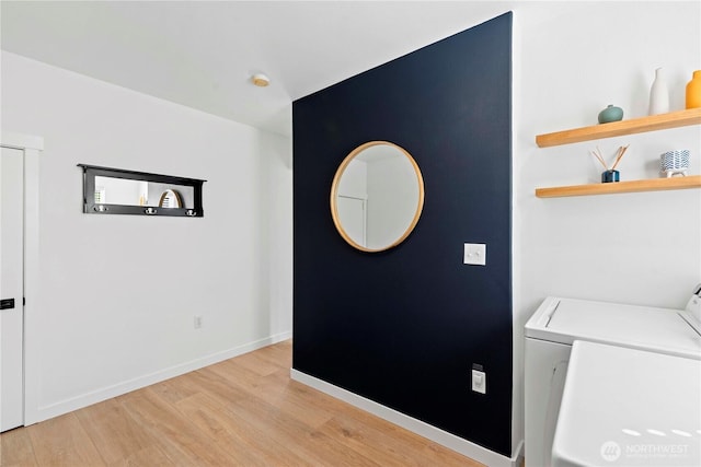 washroom with washing machine and dryer, baseboards, light wood-style floors, and laundry area