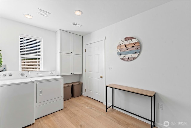 laundry room featuring light wood-type flooring, visible vents, washer and clothes dryer, and cabinet space