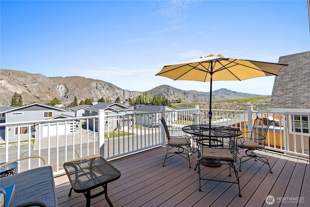 wooden deck with a residential view, outdoor dining space, and a mountain view