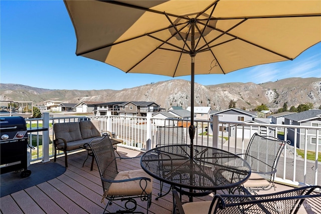 wooden terrace featuring a residential view, outdoor dining area, a grill, and a mountain view