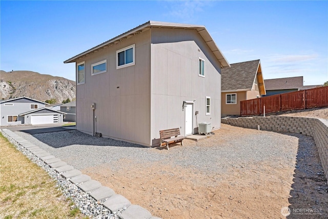 view of side of property featuring a detached garage, central AC unit, fence, and a mountain view