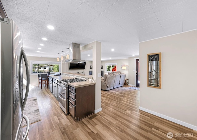 2376 Forest View Dr, Bellingham, WA 98229 - kitchen featuring appliances with stainless steel finishes, island exhaust hood, light wood-style floors, dark brown cabinetry, and open floor plan