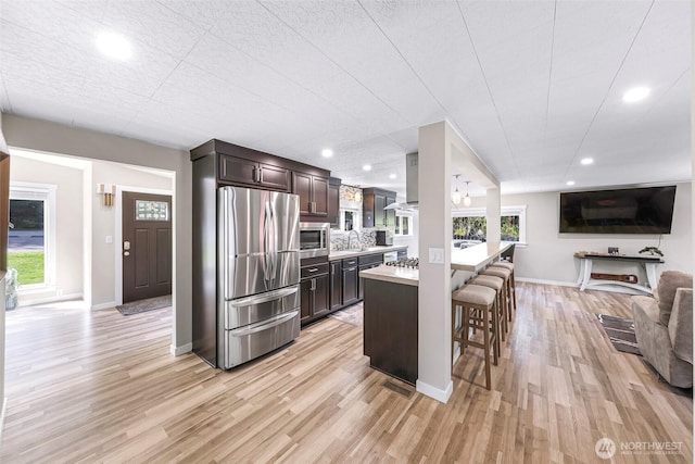 2376 Forest View Dr, Bellingham, WA 98229 - kitchen with stainless steel appliances, a kitchen bar, dark brown cabinetry, light countertops, and light wood-style flooring