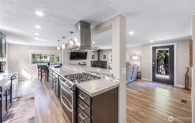 2376 Forest View Dr, Bellingham, WA 98229 - kitchen with island exhaust hood, range with two ovens, a wood stove, light wood-type flooring, and light countertops