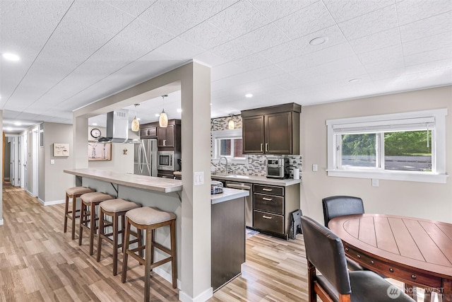 2376 Forest View Dr, Bellingham, WA 98229 - kitchen featuring a kitchen bar, light wood-style floors, appliances with stainless steel finishes, light countertops, and dark brown cabinets
