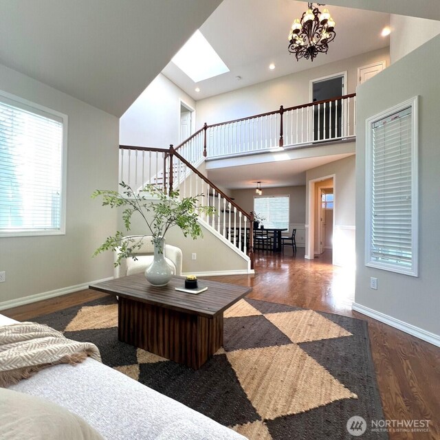 living room with stairs, an inviting chandelier, a healthy amount of sunlight, and wood finished floors