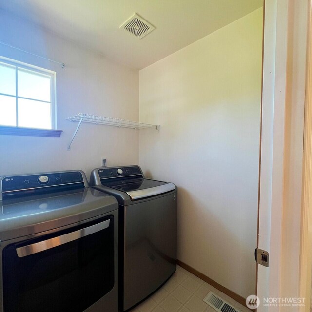 laundry area with baseboards, laundry area, visible vents, and washer and clothes dryer