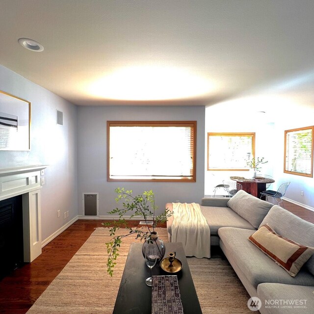 living room featuring visible vents, dark wood finished floors, and baseboards