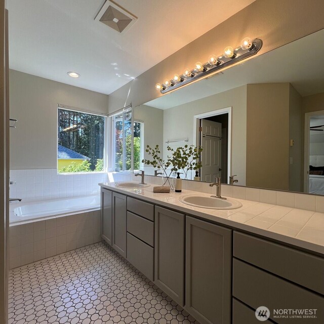 full bathroom featuring a garden tub, a sink, and double vanity