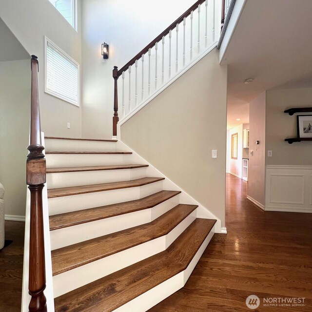 stairway with baseboards, a high ceiling, and wood finished floors