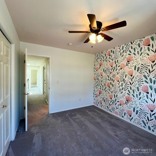 empty room with dark colored carpet, baseboards, and ceiling fan