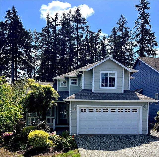 traditional home featuring a garage, roof with shingles, driveway, and covered porch