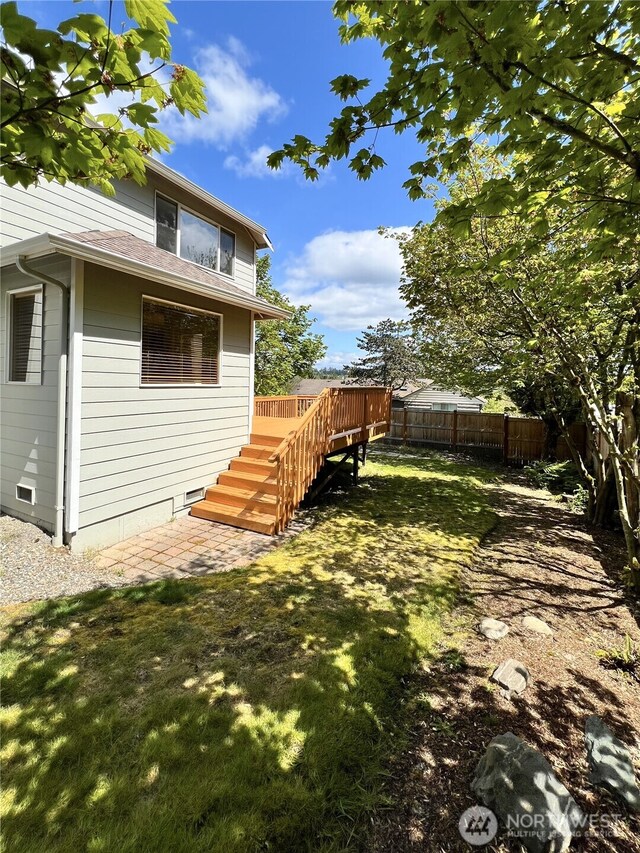 exterior space with a yard, fence, a wooden deck, and stairs