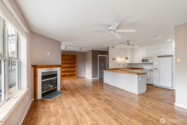 350 Castellano Way Unit 204, Port Townsend, WA 98368 - kitchen with light wood finished floors, white cabinets, a fireplace with flush hearth, a sink, and white appliances