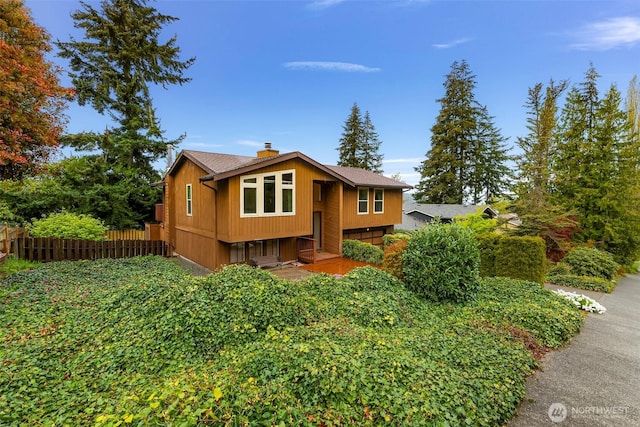 bi-level home featuring fence and a chimney