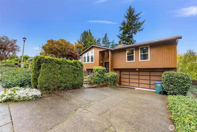 split foyer home with a chimney, driveway, and a garage