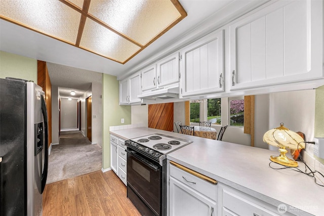 kitchen featuring under cabinet range hood, light countertops, stainless steel fridge, light wood-style flooring, and black electric range oven