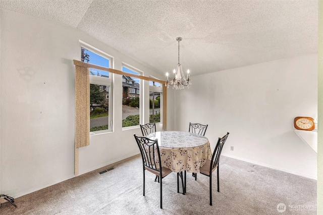 carpeted dining space featuring an inviting chandelier, a textured ceiling, visible vents, and baseboards