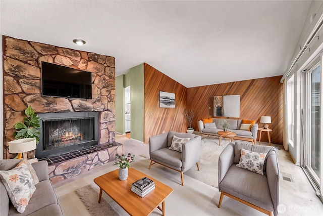living room featuring a stone fireplace, visible vents, and wood walls