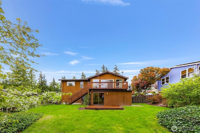 rear view of house featuring a lawn, fence, stairway, and a deck