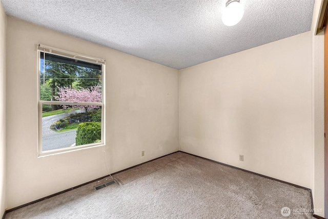 spare room with a textured ceiling, carpet flooring, baseboards, and visible vents