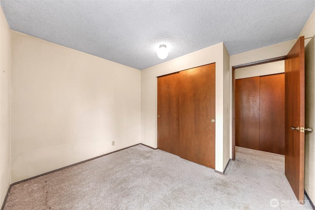 unfurnished bedroom featuring baseboards, a closet, a textured ceiling, and carpet