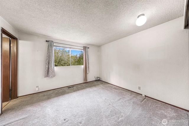 empty room with carpet floors, a textured ceiling, and visible vents