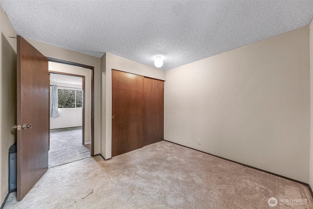 unfurnished bedroom featuring carpet flooring, a textured ceiling, and a closet
