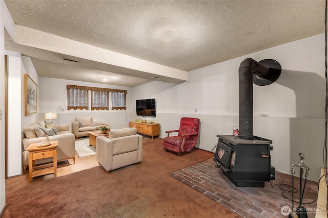 living area featuring carpet floors, a wood stove, a textured ceiling, and visible vents