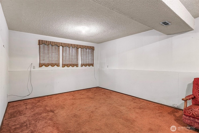 carpeted spare room with a textured ceiling and visible vents