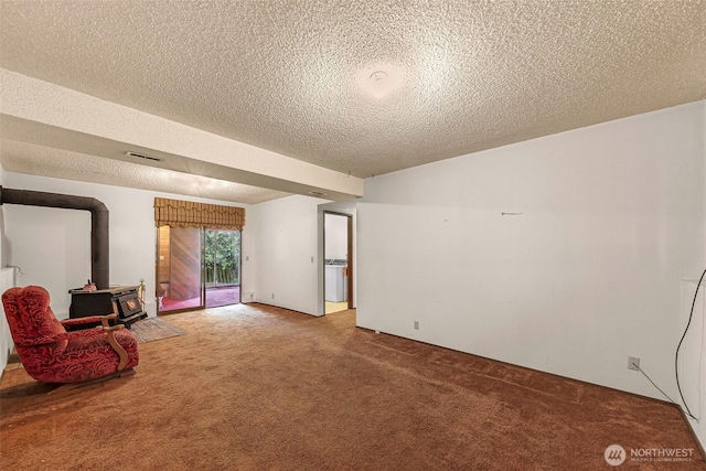 sitting room featuring a wood stove, a textured ceiling, visible vents, and carpet