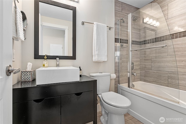 bathroom featuring vanity, enclosed tub / shower combo, wood finished floors, and toilet