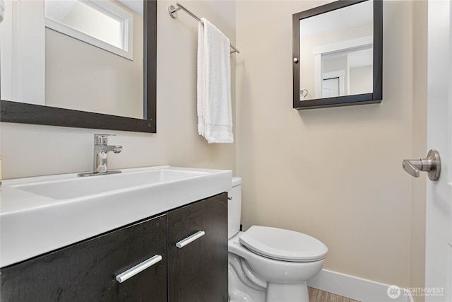 bathroom featuring baseboards, vanity, and toilet