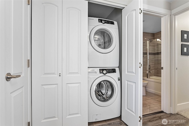 laundry room with stacked washer and dryer, laundry area, and dark wood-type flooring
