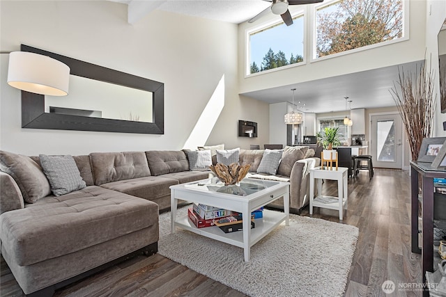 living room with dark wood-style flooring, ceiling fan, and a towering ceiling