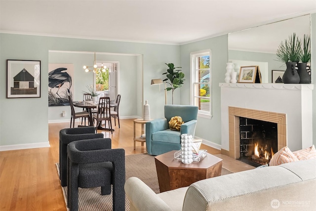 living room featuring baseboards, a fireplace with flush hearth, crown molding, and wood finished floors