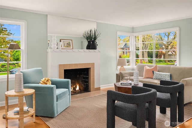 sitting room featuring baseboards, a fireplace with flush hearth, and wood finished floors