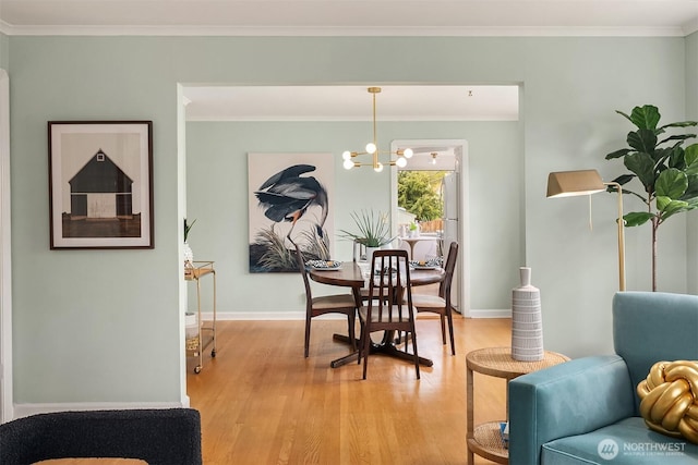 dining space with baseboards, a chandelier, ornamental molding, and light wood finished floors